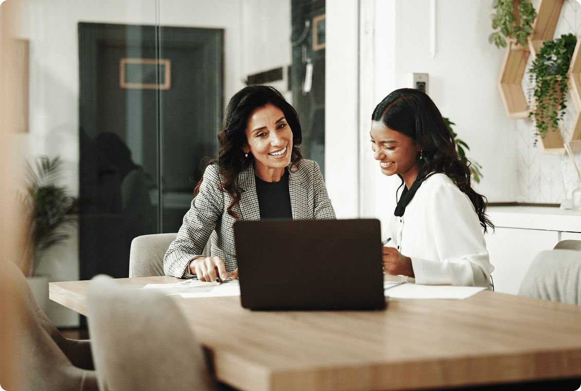 Two women smiling at office desk
